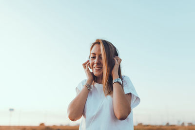 Portrait of smiling young woman against clear sky