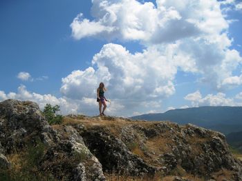 Woman standing on rock against sky