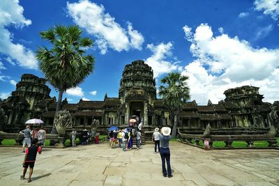 Tourists at angkor wat temple against sky