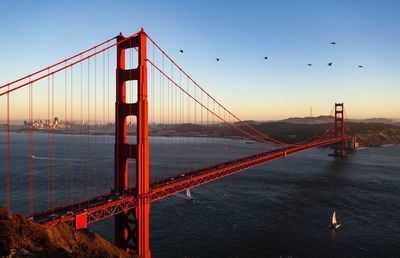 Suspension bridge in city at sunset