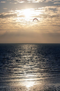 Scenic view of kitesurfer at sea against sky during sunset