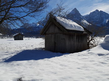 House on snow covered landscape against sky