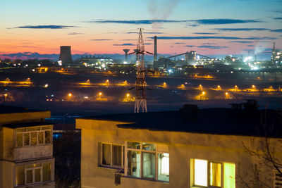 Illuminated city against sky at sunset