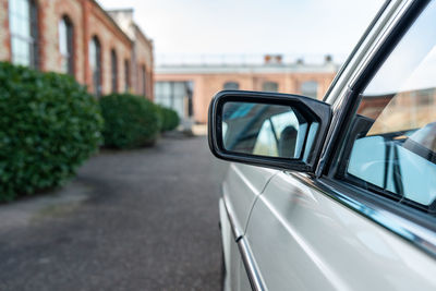 Side mirror of a white car with brick buildings in the background