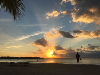 Silhouette people on beach against sky during sunset