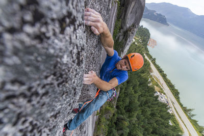 Climber doing hard move on multipitch with ocean view and exposed