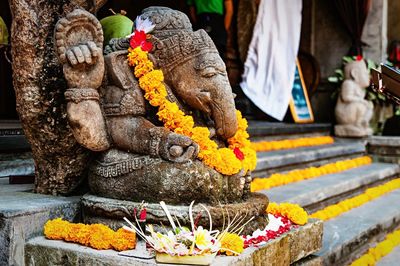 Close-up of marigold garland on ganesha statue at temple in ubud