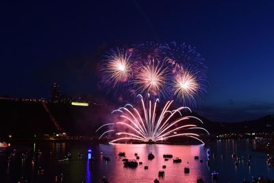 Firework display in city against sky at night