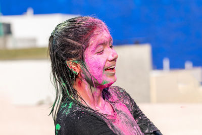 Side view of young girl looking away while celebrating holi festival