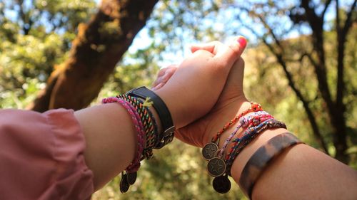 Cropped hands of couple holding hands against trees