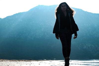 Portrait of young woman standing against mountain