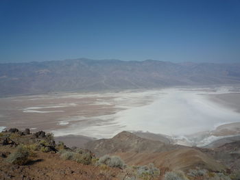 Scenic view of land and mountains against clear sky