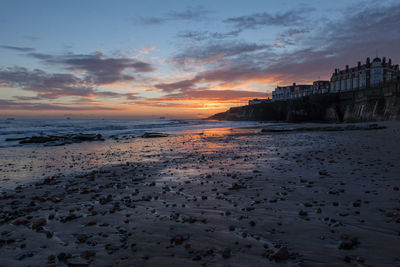 Stones on beach against cloudy sky at dusk