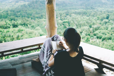 Young woman using mobile phone while sitting on bench