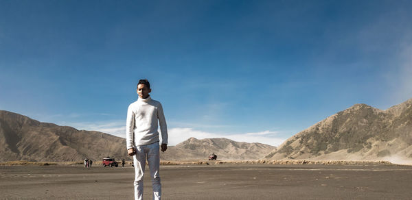 Portrait of man standing at desert against mountain 