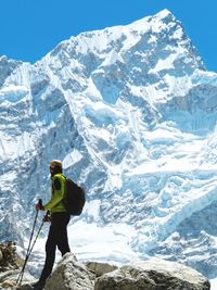 Man standing on snowcapped mountain against sky