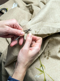 High angle view of woman cutting thread on textile