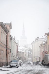 Cars on street amidst buildings in city against sky