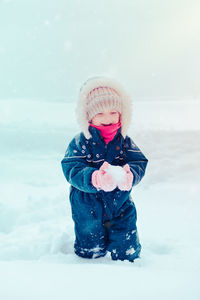 Cute girl wearing warm clothing playing with snow during winter