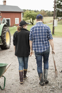 Rear view of farming couple walking on rural road