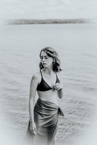 Portrait of young woman standing against sea