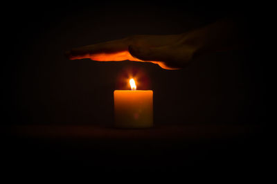 Close-up of illuminated tea light candle in darkroom