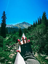 Cropped hand of woman gesturing stop gesture on land against clear blue sky