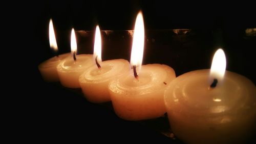 Close-up of lit candle over black background