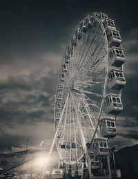 Low angle view of ferris wheel against cloudy sky