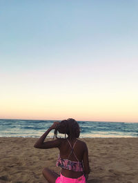 Rear view of woman at beach against clear sky