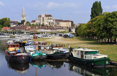 Boats moored on river by buildings in city against sky