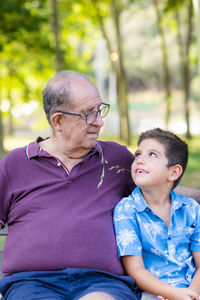 Grandfather and his grandson sitting on a bench in the park