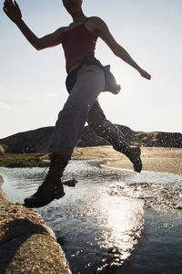 Low angle view of man jumping on beach against sky