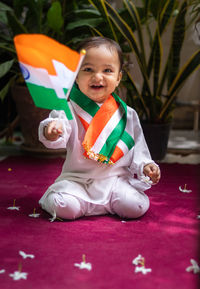 Cute toddler holding indian tricolor flag in traditional cloth with innocent facial expression