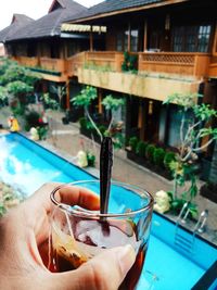 Person holding drink by swimming pool