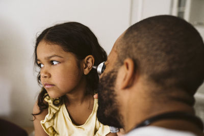 Male healthcare worker examining girl's ear at medical clinic