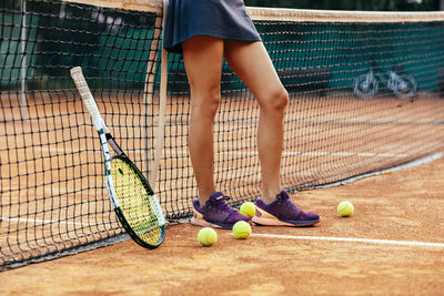 Female tennis player leaning on net at sports court