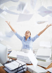 Happy woman throwing documents in office