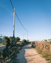 Road amidst field against clear sky