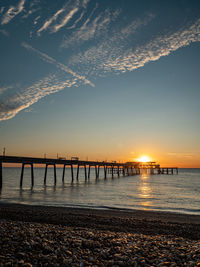 Pier over sea against sky during sunset