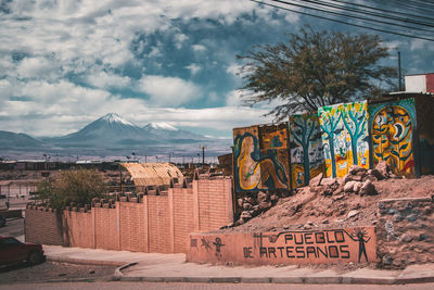 Graffiti on tree by mountain against sky