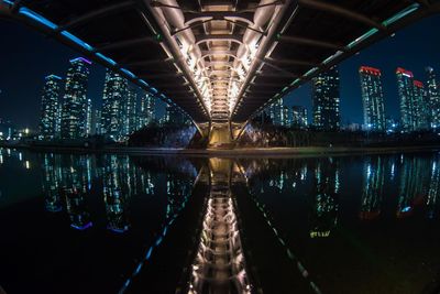 Illuminated bridge over river in city at night