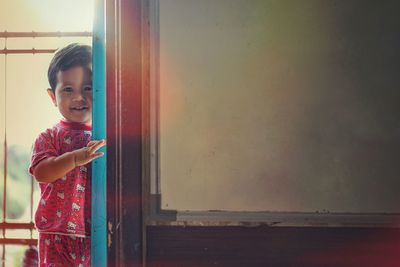 Portrait of boy looking away while standing on wall