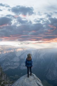 Rear view of man standing on mountain against sky