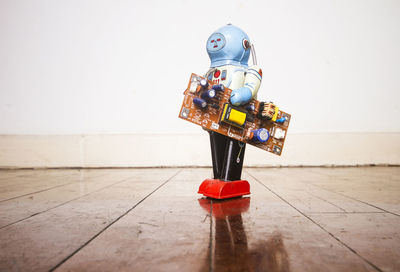 Close-up of toys on hardwood floor against wall