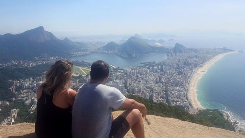 Rear view of people looking at sea by cityscape against sky