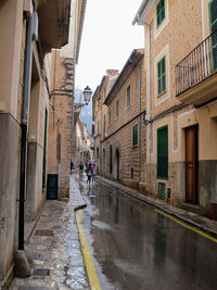 People walking on wet street amidst buildings during monsoon