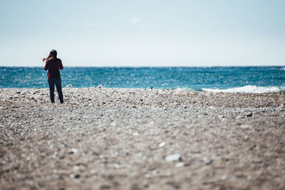 Rear view of woman standing at beach