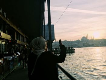 Rear view of man and woman on city at sunset