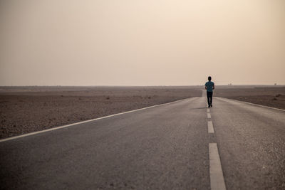 Rear view of man on road against sky